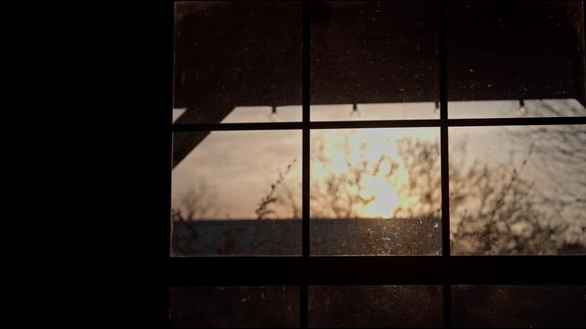 Old rustic window in the evening with the sunset peeking through
