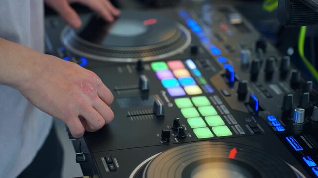 Talented disc jockey performing technical scratching techniques and mixing music on digital console