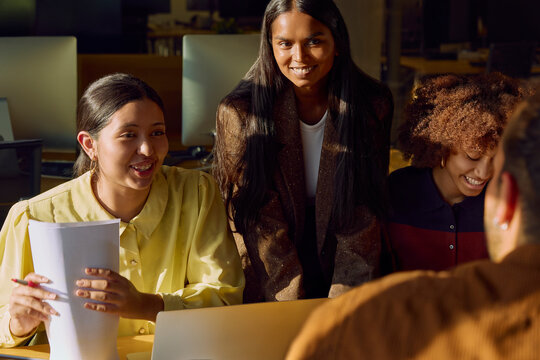 Coworkers collaborating during team meeting with laptop and documents