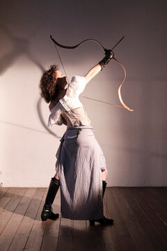 Woman practices archery in a simple indoor setting