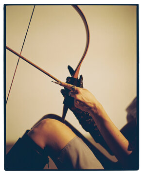 Bow and arrow held by a hand in a studio setting