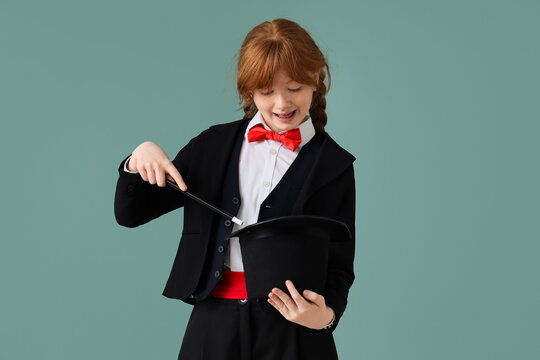 Young magician showing magic trick with hat on green background