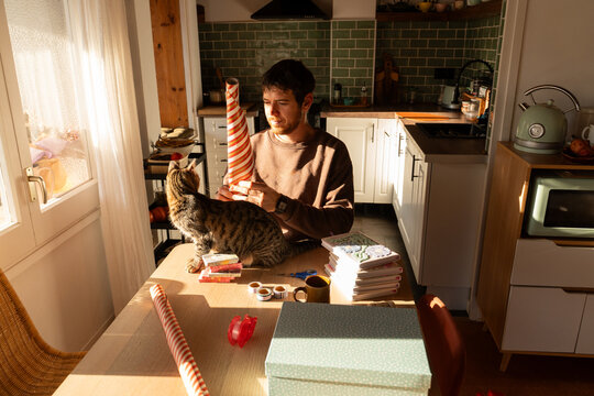Man wrapping gift with cat