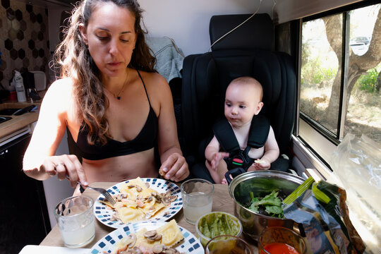 Mother and baby eating ravioli in camper van