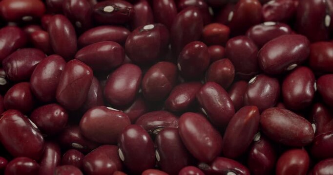 Detailed macro shot of raw red kidney beans rotating in slow motion, highlighting their texture and deep color as a background for healthy cooking concepts and nutritional information
