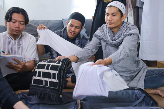 Three Muslim Men Packing Muslim Prayer Clothing Into Suitcases For Eid Holiday Celebration