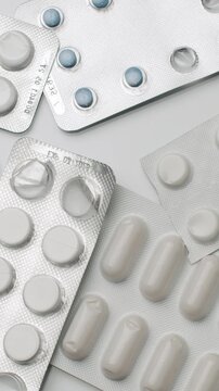 Numerous blisters with multicolored pills and tablets rotating on a white background, symbolizing healthcare, pharmaceutical industry, and medication concepts for medical treatment