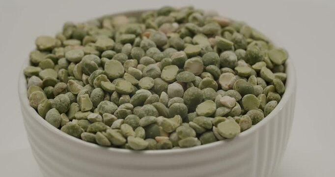 Green dried split peas rotating slowly. Raw green split peas rotating in a bowl in a detailed close-up shot, showcasing the texture and color of the healthy, nutritious, and protein-rich vegetarian