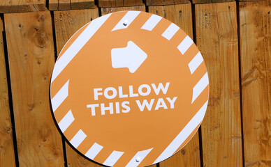 Follow This Way outdoor informational signage on wooden fence