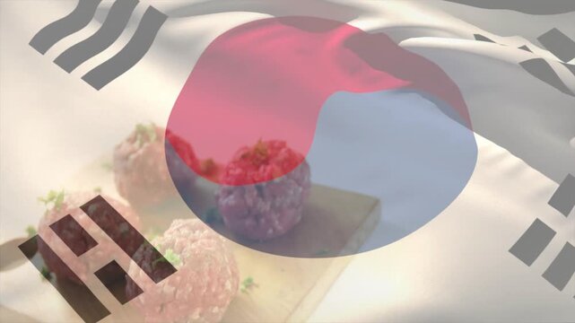 Taegukgi overlay appearing then rippling and folding over tabletop, revealing three pink rice balls