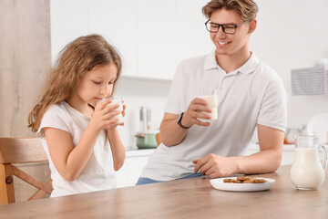 Little girl with her father drinking milk in kitchen