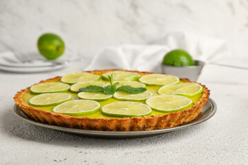 Plate of tasty lime tart with mint on white background