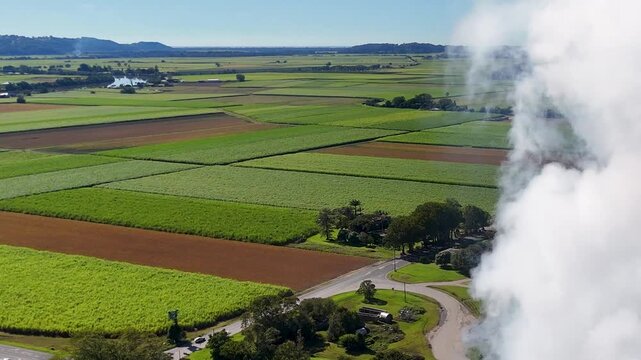 Aerial View of White Smoke Drifting Over Lush Green Farmland