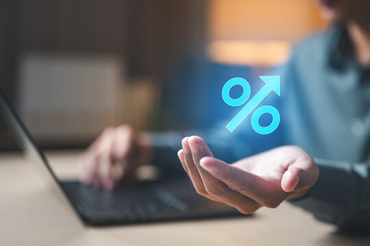 Interest rate and savings growth concept showing percentage increase symbol above hand and laptop, representing APY comparison, investment returns, banking dashboard analysis, and financial planning.