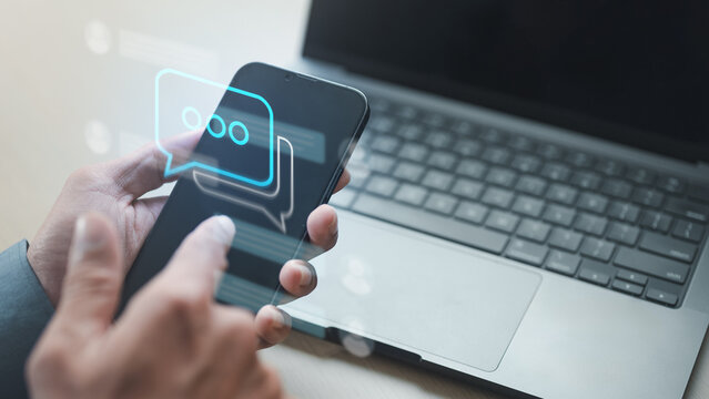 Close-up of person using smartphone with chat bubble interface overlay. Concept of social media communication, online messaging, customer support, digital interaction, and mobile networking technology
