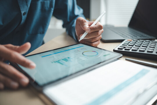 Business professional analyzing financial data on digital tablet dashboard with calculator and laptop, representing accounting software, ERP system integration, performance monitoring.