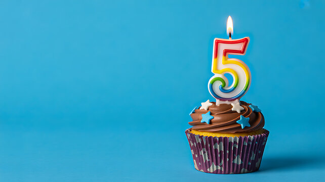 Chocolate cupcake with number five candle on blue background birthday celebration concept 