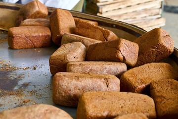 Freshly baked rye loaves cooling on racks in a bustling bakery plant during the morning hours