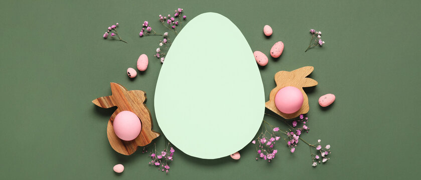 Composition with egg-shaped blank card, Easter eggs and gypsophila flowers on green background