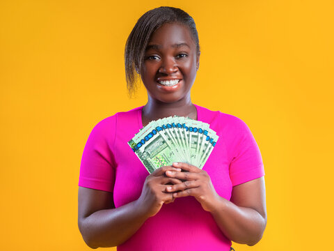 A smiling Black African woman displays a fan of Libyan Dinar banknotes against a vibrant yellow background. The image represents financial success, wealth, and economic joy in Libya.