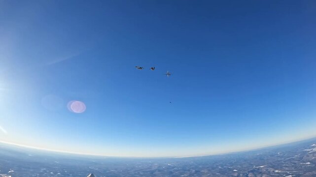 Skydivers leave the plane and begin their free fall in a clear blue sky &ndash; a dynamic shot for extreme sports and travel themes.
