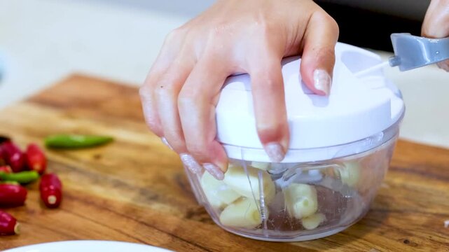Close Up of Hands Using Manual Pull String Food Chopper for Garlic