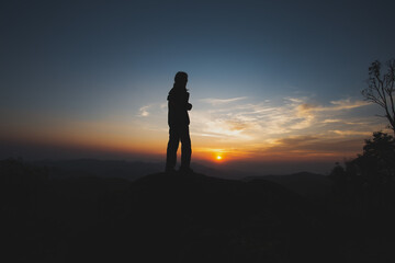 Obraz premium Contemplative silhouette of person standing alone on mountain top. serene view of beautiful sunset sky, feeling freedom and solitude in nature at dusk