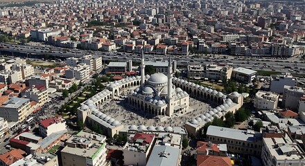 An aerial view of a majestic multi-domed mosque complex nestled within a dense urban landscape and busy city highway.
