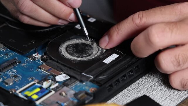 Preventive laptop repair removing dust from internal cooling fan to avoid overheating and maintain efficient computer operation close up view