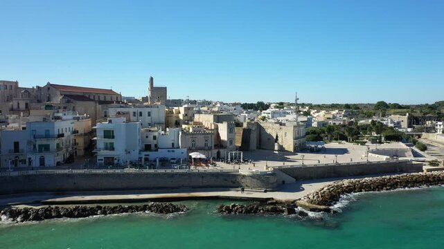 Scenic view of Otranto s historic waterfront with turquoise sea, traditional buildings, and clear blue sky on a sunny day in southern Italy.