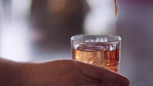 Beverage making. Refreshing alcohol. Tropical aperitif orange drink in wide glass. Barman hands sprinkling aromatic juice serving cocktail.