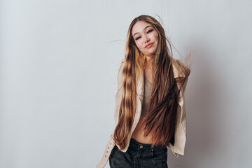 Fototapeta premium Young woman with long hair and casual jacket posing with smile against neutral background. Fashion, beauty, hair care and youth style concept with confident female portrait.