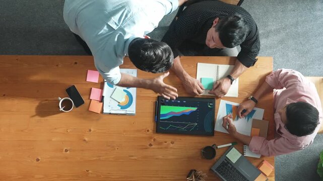 Top aerial view of diverse business team talking and brainstorming marketing idea while colleague walking and joining meeting. Professional people solving problem and looking at report. Convocation.