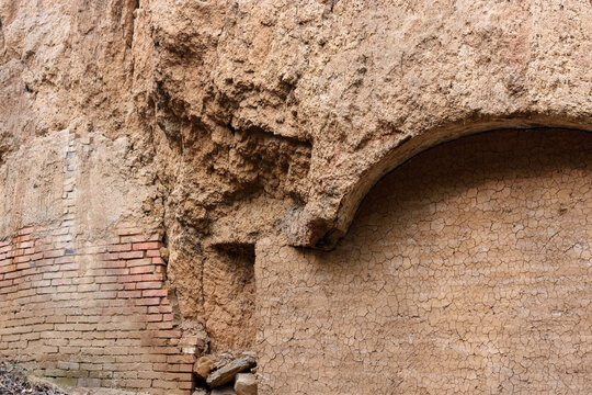 Weathered adobe ruin wall with brick arch detail