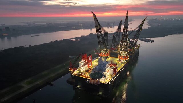 Rotterdam, Netherlands. Drone flight over industrial area with cargo ports, containers and a semi-submersible ship, heavy lifting crane. Machines designed for work at sea