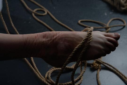 Shibari art shown through ropes tied on a woman's foot in a simple space