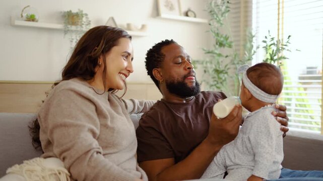 A happy couple treasures moments together, as the father lovingly feeds their baby girl while the mother watches with joy. Their bond shines brightly in this delightful family time at home.