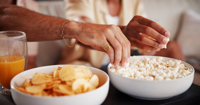 Hands, friends and eating popcorn in home with bonding, relax and break with bowl in lounge. People, share snacks and chips with drinks, reunion or chill in living room on weekend at apartment