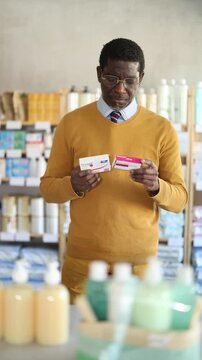  Adult man buyer chooses box of paracetamol tablets in pharmacy