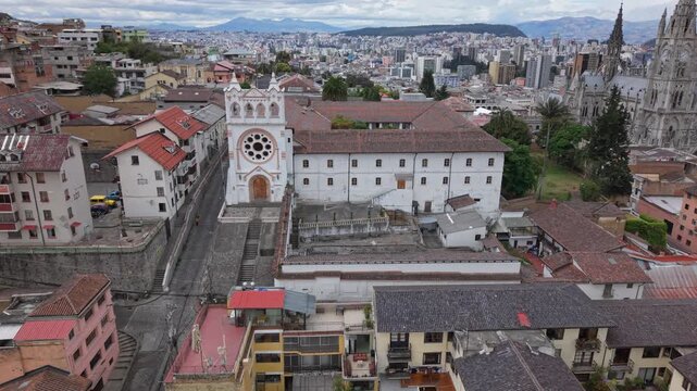 Drone pulls backs from Monastery of The Incarnation of St. John with Basilica del Voto Nacional visible in background, Quito historic center, Ecuador.