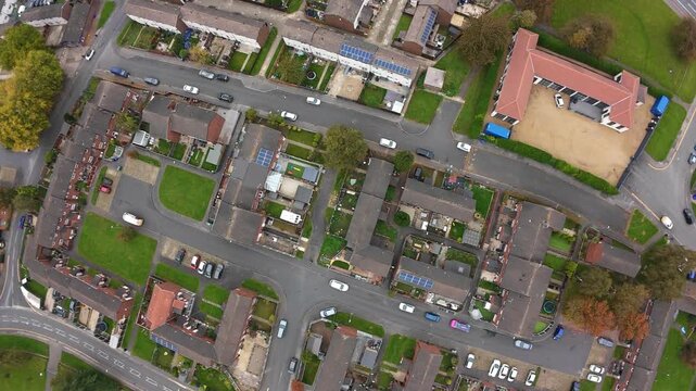 Aerial Drone View Leeds Residential Rooftops Showing Terraced Houses, School With Playground, Parked Cars Along Narrow Streets, Small Gardens, Green Patches, Autumn Trees, Overhead Mapping Perspective