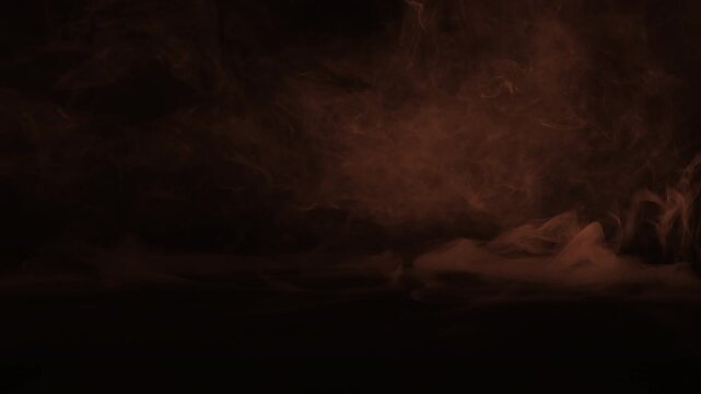 Cinematic low-lying orange smoke and ground fog flowing across the floor on a black background for spooky atmospheric VFX