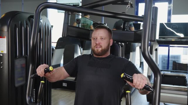 Male athlete doing chest flyes on cable machine in gym