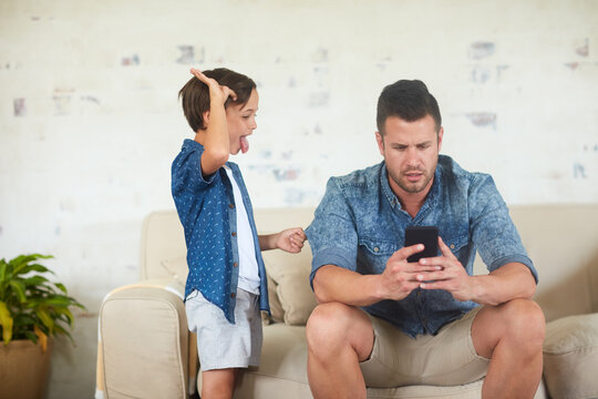 Dad, child and ignore with phone on sofa for distraction, attention seeking or neglecting in home. Father, kid or annoyed with mobile smartphone for anti social behaviour or doom scrolling in house