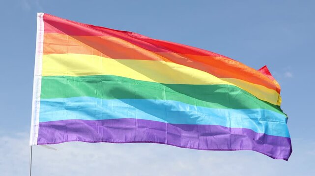  LGBT flag waving against the blue sky close-up
