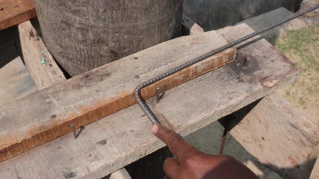 worker manually bends steel reinforcement bars