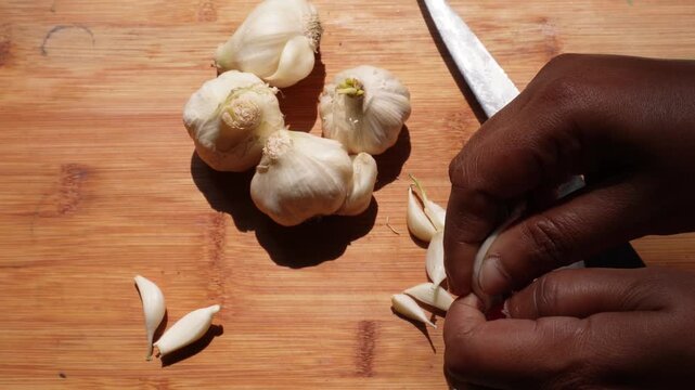 Fresh garlic bulbs and cloves prepared on wooden cutting board