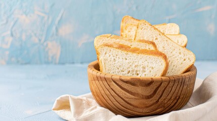 Fototapeta premium Freshly Sliced White Bread in a Wooden Bowl on a Light Blue Background