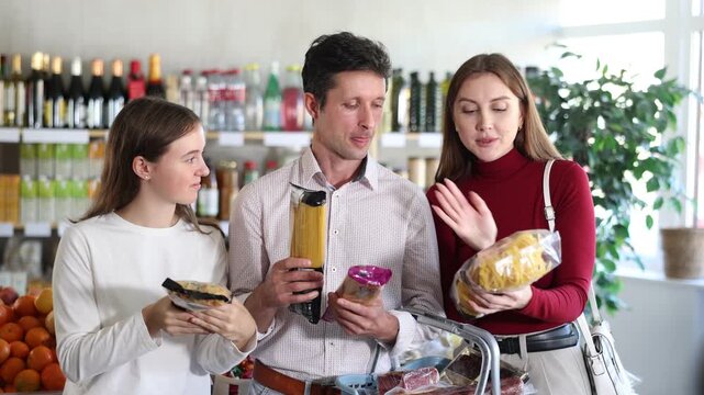Happy teen girl with her parents deciding between packages of pasta in supermarket
