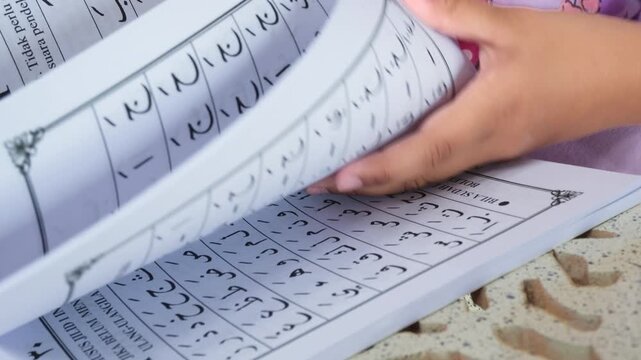 Close up of a child's hand reciting the Iqro Book